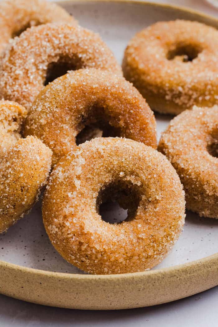 Soft Baked Apple Cider Donuts made healthier with whole wheat flour, applesauce and Greek yogurt for the perfect fall treat that comes together in just 20 minutes! Loaded with warm spices and coated with cinnamon and sugar!