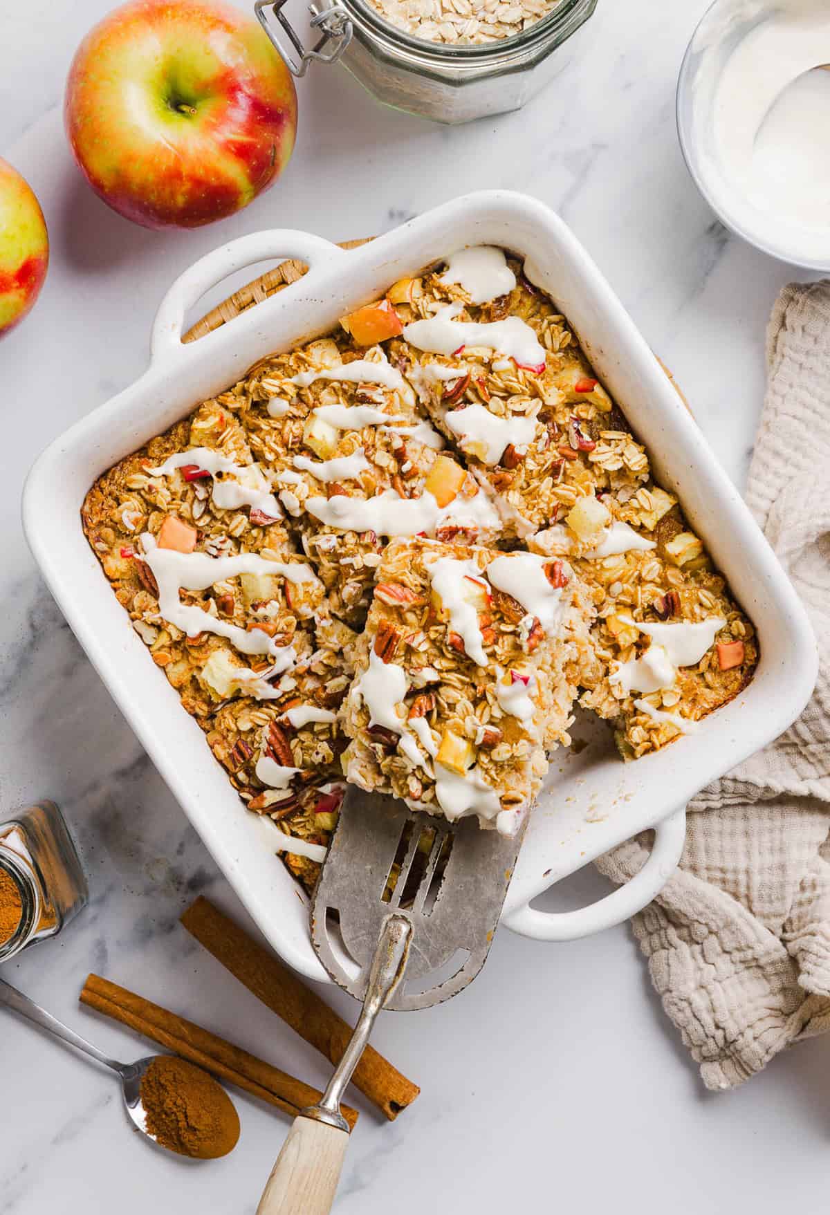 This Apple Cinnamon Baked Oatmeal is a cozy breakfast made with wholesome oats, shredded apples, and warm spices while naturally sweetened with maple syrup and plump raisins!  We also topped this with crunchy pecans and a delicious maple cream cheese glaze!